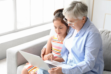 Poster - Little girl with her grandma using laptop at home