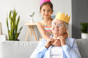 Little girl with her grandma in paper crowns at home