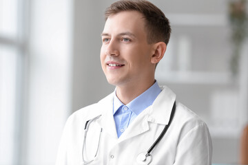 Wall Mural - Male medical assistant with stethoscope smiling in clinic