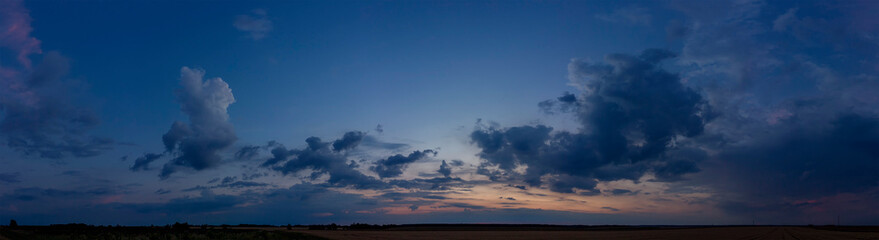 A wide majestic view of a panoramic dark sunset over the fields
