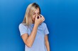 © Krakenimages.com - Beautiful blonde woman wearing casual t shirt over blue background tired rubbing nose and eyes feeling fatigue and headache. stress and frustration concept.