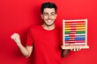 © Krakenimages.com - Young hispanic man holding traditional abacus screaming proud, celebrating victory and success very excited with raised arm