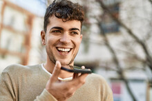 Young Hispanic Man Sending Voice Message Using Smartphone At The City