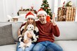 © Krakenimages.com - Young couple of wife and husband sitting on the sofa wearing christmas hat at home celebrating victory with happy smile and winner expression with raised hands