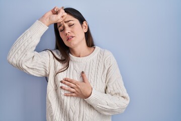 Poster - Young brunette woman standing over blue background touching forehead for illness and fever, flu and cold, virus sick