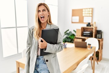 Wall Mural - Blonde business woman at the office angry and mad screaming frustrated and furious, shouting with anger. rage and aggressive concept.