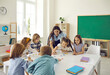 © Studio Romantic - Modern education. Female teacher and junior high school students have fun putting together puzzles in class. Little girls and boys sit in a classroom around the table and play fun games in class.