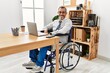 © Krakenimages.com - Middle age hispanic man working at the office sitting on wheelchair looking away to side with smile on face, natural expression. laughing confident.