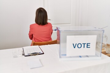 Sticker - Beautiful middle age hispanic woman at political election sitting by ballot standing backwards looking away with crossed arms