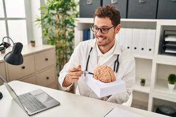 Sticker - Young hispanic man wearing doctor uniform having video call holding brain at clinic