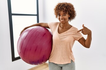 Sticker - Young african american woman holding pilates ball pointing finger to one self smiling happy and proud