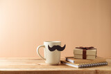 Fototapeta Kawa jest smaczna - Father's day concept with coffee cup, mustache, notebook and gift box on wooden table over beige background