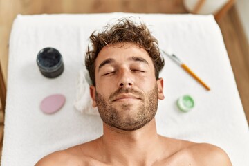 Poster - Young hispanic man having facial treatment at beauty center