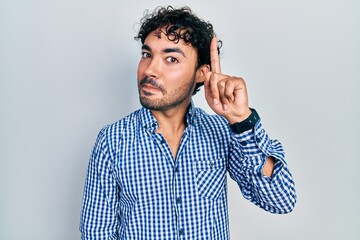 Sticker - Young hispanic man wearing casual clothes pointing finger up with successful idea. exited and happy. number one.