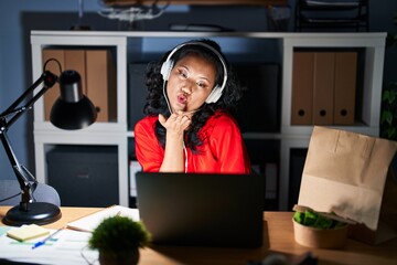 Sticker - Young asian woman working at the office with laptop at night looking at the camera blowing a kiss with hand on air being lovely and sexy. love expression.