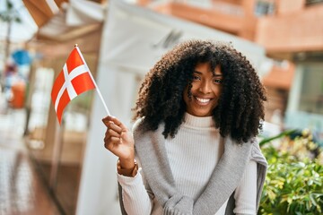 Canvas Print - Young african american woman smiling happy holding Denmark flag at the city.