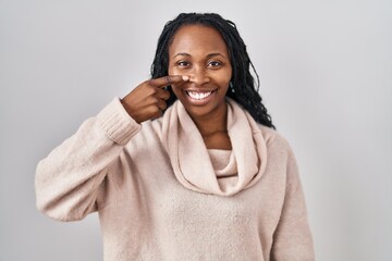 Canvas Print - African woman standing over white background pointing with hand finger to face and nose, smiling cheerful. beauty concept