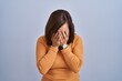 © Krakenimages.com - Middle age brunette woman standing wearing orange sweater with sad expression covering face with hands while crying. depression concept.