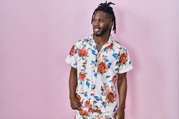 Poster - African man with dreadlocks wearing summer shirt over pink background looking away to side with smile on face, natural expression. laughing confident.