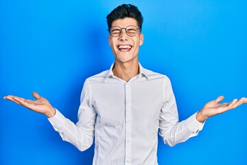 Sticker - Young hispanic man wearing casual clothes and glasses celebrating mad and crazy for success with arms raised and closed eyes screaming excited. winner concept