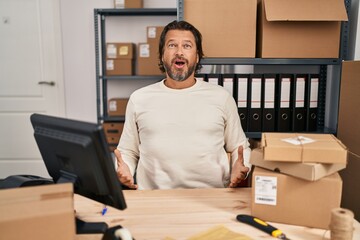 Sticker - Handsome middle age man working at small business ecommerce afraid and shocked with surprise expression, fear and excited face.