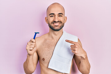 Canvas Print - Young bald man shirtless holding razor smiling happy pointing with hand and finger