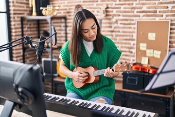 Sticker - Young hispanic woman musician playing ukulele at music studio