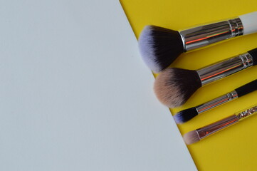 Sticker - Professional cosmetic makeup brushes of different sizes on a yellow background for applying powder, shadows and blush and other cosmetic products