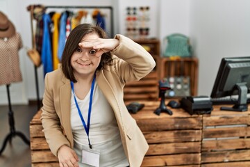 Poster - Young down syndrome woman working as manager at retail boutique very happy and smiling looking far away with hand over head. searching concept.