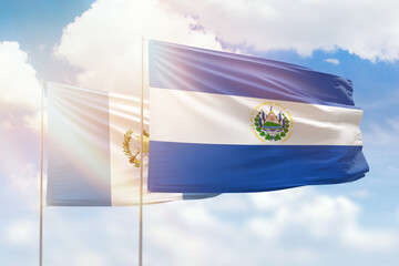 Sunny blue sky and flags of el salvador and guatemala