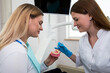 © Tania - a woman dentist shows a young girl a model of an artificial jaw.