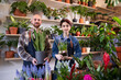 In front of tue camera in the floral store the sale assistant man and the florist lady have a conversation while analysing the flowers form the pot