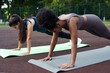 © etonastenka - Two fitness women of different nationalities in a plank position in an outdoor stadium. Push ups.