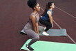 © etonastenka - Two female friends do squats with dumbbells outdoors at the stadium.