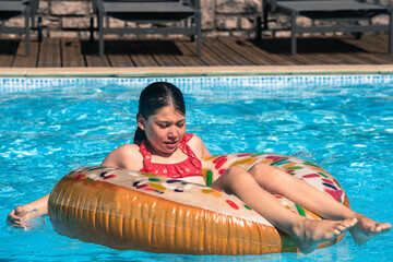 Sticker - pretty young girl playing with her donut-shaped buoy in the swimming pool