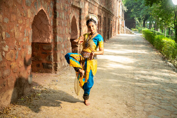 Indian woman Odissi dancer doing classical dance form outdoor at heritage place. Orissi dance. art and culture of india.