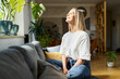 © baranq - Happy adult woman sitting on the sofa with eyes closed enjoying bright daylight