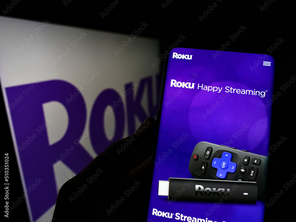 Stuttgart, Germany - 03-01-2022: Person holding cellphone with website of American video streaming company Roku Inc. on screen in front of logo. Focus on center of phone display.