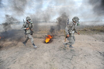 Almaty, Kazakhstan - 08.22.2012 : Soldiers pass a burning obstacle course in gas masks.