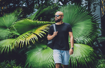 Portrait of a fashion young man at beautiful green leaves background in jungle