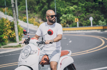 Wall Mural - Stylish young man with his motorbike on the road