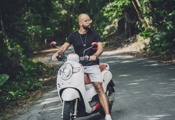 Wall Mural - Stylish young man and his motorbike on the road in the jungle