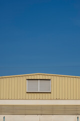 Wall Mural - Aluminum louvers on steel wall of warehouse building against blue clear sky in minimal style and vertical frame