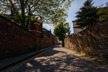 Leeds UK - 15.05.2018: Leeds paved cobblestone English alleyway with warm light peeking through trees