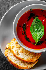 Wall Mural - cold tomato soup with basil in a bowl on Dark grey black slate background