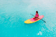 Attractive woman in pink swimwear floating on stand up paddle board on a quiet ocean. SUP surfing with woman in tropical sea