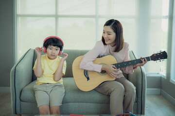 Smiling young parents and their child are very happy, Mum sings a song and playing to children. Happy family