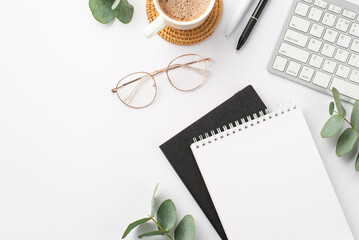 Business concept. Top view photo of workplace keyboard black and white stationery note pads pens cup of coffee on rattan placemat glasses and eucalyptus on isolated white background with blank space