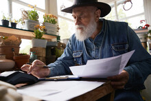 Aged Male Florist Making Financial Reports In Own Shop