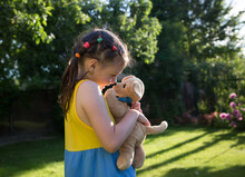 Cute Girl Of 6-7 Years Old Plays Nose To Nose With Her Plush Dog. Child On A Walk In The Park On A Sunny Summer Day. Summer Mood, Happy Childhood. Favorite Toy, Tendern